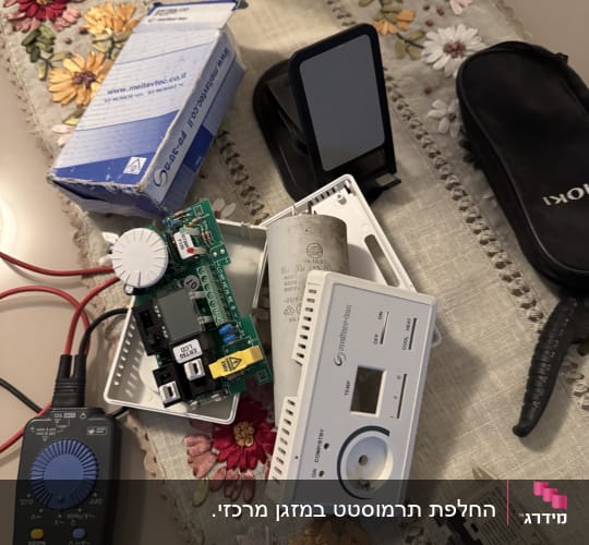 חלקי אלקטרוניקה וכלים על שולחן עם מפה פרחונית
